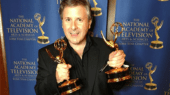 A person in a black shirt holds two awards in front of a backdrop that reads "The National Academy of Television Arts & Sciences Lone Star Chapter.