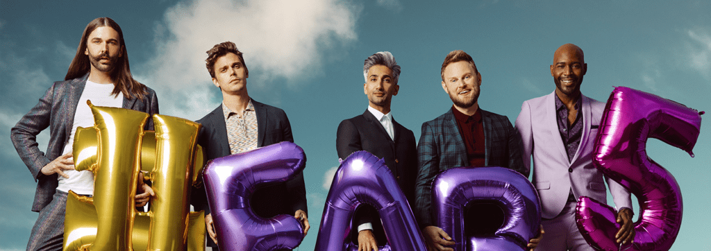 Five people holding inflated balloons that spell "HEARTS" against a blue sky background.