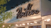 The image shows the exterior of a building with the name "Poitan" displayed on a sign. The area around it is illuminated by string lights, and there is a tree on the left side.