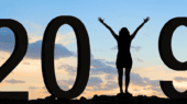 A person stands between large numbers "2019" with arms raised against a sunset sky background.