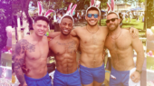 Four men wearing matching blue shorts and pink bunny ears pose together outdoors at a festive event.