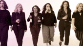 Six women holding wine glasses and walking forward in a confident manner, each wearing casual to semi-formal clothing.