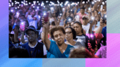 A crowd of people holding up smartphones with flashlight apps turned on, creating a sea of lights. The background is a mix of blue and purple gradient patterns.