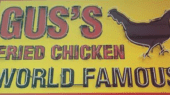 Sign reading "Gus's Fried Chicken World Famous" with a chicken silhouette, against a yellow background.