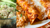 A glass bowl of chicken salad with celery sits next to a plate with two enchiladas covered in melted cheese, accompanied by a serving of rice.