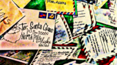 A pile of colorful letters addressed to Santa Claus, including one with the address "Santa Claus, P.O. Box 56099, North Pole, Alaska 99705.