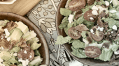 Two plates of salad on a table with silverware.