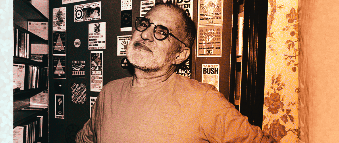 A man with glasses is standing in front of posters.