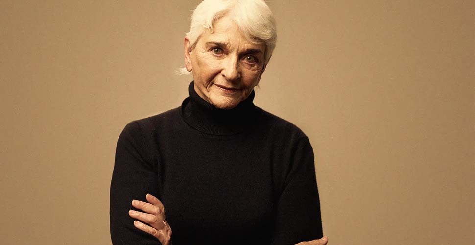 A woman with white hair wearing black sweater.