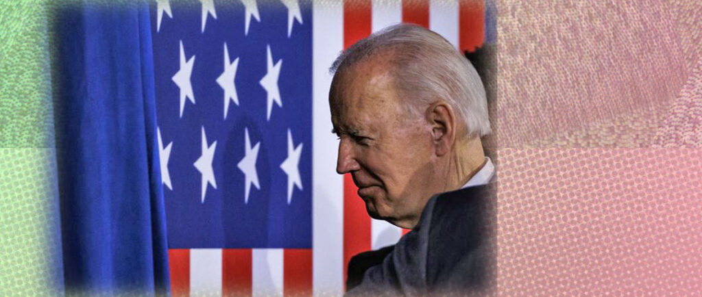 Joe Biden walking on a stage with a huge American flag
