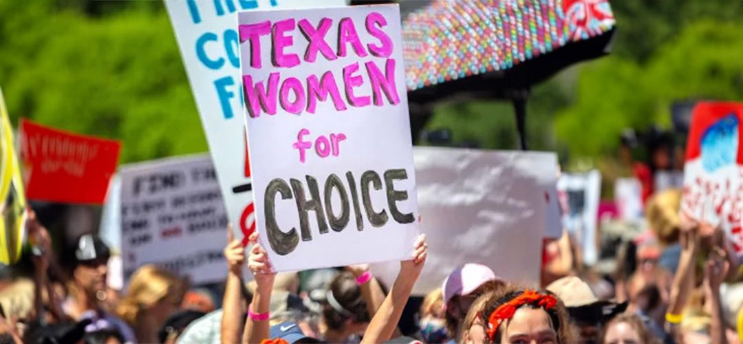 A woman holding up a sign that says texas women for choice.